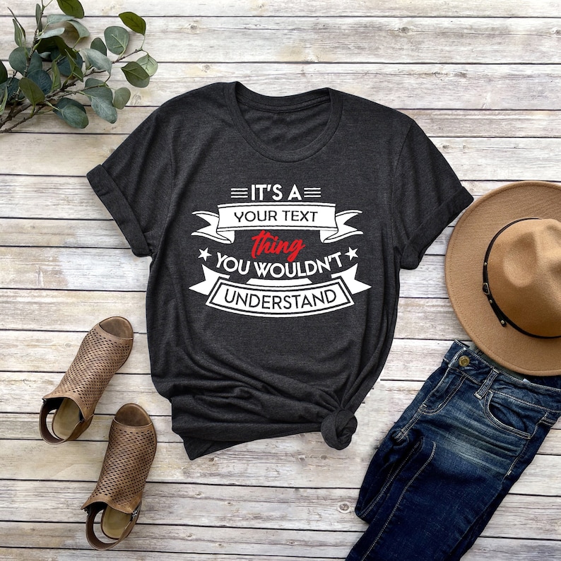 K&ouml;nnte beinhalten: Ein dunkelgraues T-Shirt mit wei&szlig;em Text, der lautet "It's a [your text] thing you wouldn't understand". Der Text ist von einem wei&szlig;en Band mit roten Sternen umgeben.