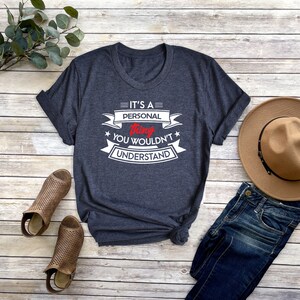K&ouml;nnte beinhalten: Ein dunkelblaues T-Shirt mit einem wei&szlig;en Aufdruck, der "Es ist eine pers&ouml;nliche Sache, die du nicht verstehen w&uuml;rdest" sagt. Der Aufdruck ist im Vintage-Stil mit roten Akzenten.
