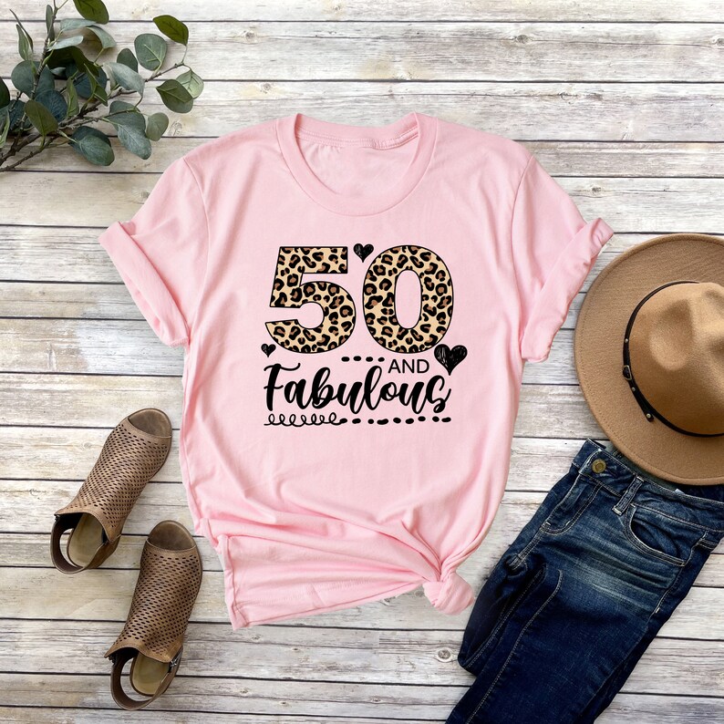 Puede incluir: Camiseta rosa con un dise&ntilde;o de estampado de leopardo con el n&uacute;mero 50 y el texto "AND Fabulous".