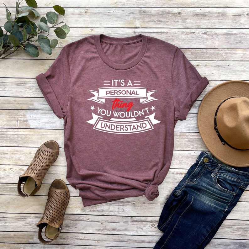 K&ouml;nnte beinhalten: Ein maroonfarbenes T-Shirt mit wei&szlig;em Text, der "It's a personal thing you wouldn't understand" lautet. Der Text ist in einem Banner-Stil mit Sternen auf beiden Seiten.