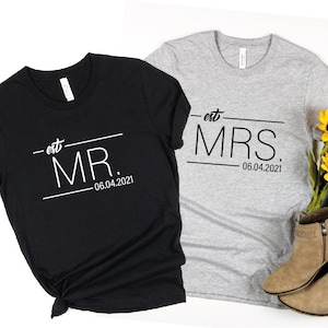 May include: Two black and gray t-shirts with the text "est. MR. 06.04.2021" and "est. MRS. 06.04.2021" printed on them.