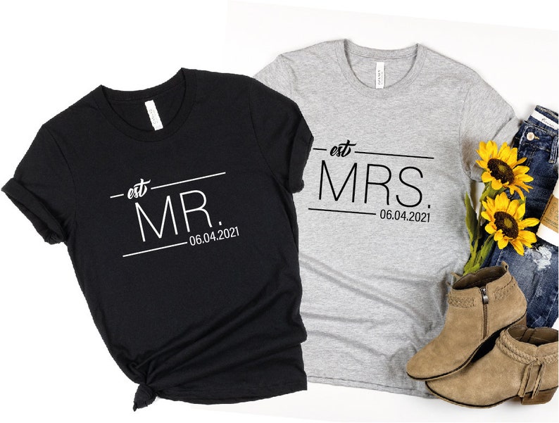 May include: Two black and gray t-shirts with the text "est. MR. 06.04.2021" and "est. MRS. 06.04.2021" printed on them.