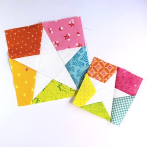 Pode incluir: Dois blocos de tecido quadrados para colcha com uma forma de estrela branca central rodeada por várias peças de algodão com padrões coloridos em tons de laranja, rosa, azul, amarelo e verde com motivos geométricos, florais e corações.