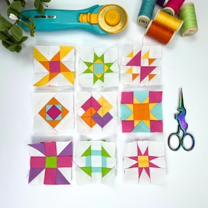 Puede incluir: Nueve cuadrados de tela coloridos con diferentes diseños de patchwork, incluyendo una estrella, una molinillo y un tablero de ajedrez. Los cuadrados están dispuestos en tres filas de tres, y están rodeados de espacio en blanco. También se puede ver un par de tijeras y un cortador rotatorio en la imagen.