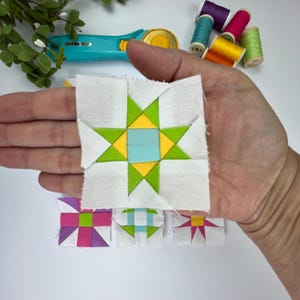 Peut inclure: Un bloc de courtepointe en tissu carr&eacute; pr&eacute;sentant un carr&eacute; central bleu clair entour&eacute; de quatre triangles jaunes et quatre triangles vert lime, le tout encadr&eacute; par des coins en tissu blanc. Trois autres blocs sont visibles en dessous.