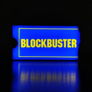 May include: A blue and yellow rectangular sign with the word "BLOCKBUSTER" in yellow letters.