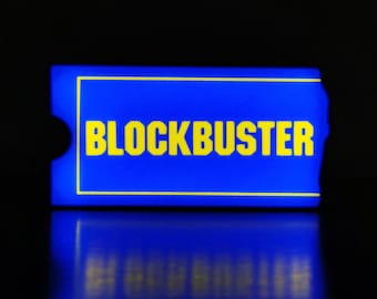 May include: A blue and yellow rectangular sign with the word "BLOCKBUSTER" in yellow letters.