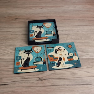 May include: A set of square coasters featuring illustrations of a black cat and a spotted dog in a room with a television, lamp, and chair. The coasters are coloured in shades of blue, orange, and black, and are stored in a black square holder.