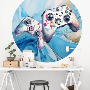Puede incluir: Una obra de arte mural redonda con dos mandos de videojuegos. Los mandos son blancos con detalles coloridos, sobre un fondo abstracto azul y blanco. El arte se exhibe en una habitación luminosa y moderna.