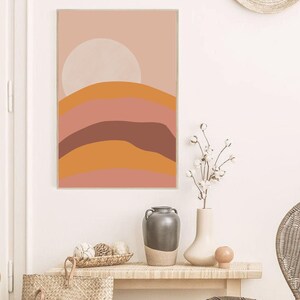 May include: Abstract art print with a pink, orange, and brown color scheme. The print features a stylized landscape with rounded hills and a large circle in the upper center.