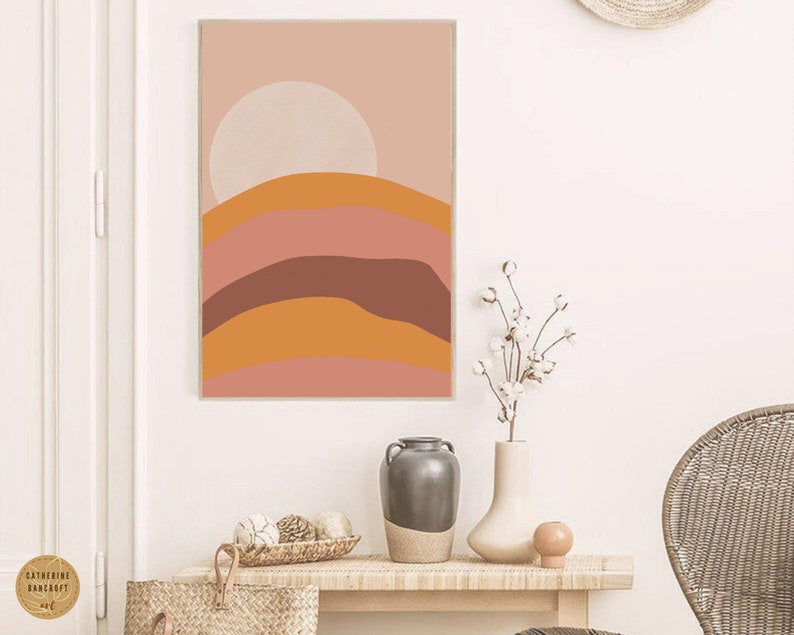 May include: Abstract art print with a pink, orange, and brown color scheme. The print features a stylized landscape with rounded hills and a large circle in the upper center.
