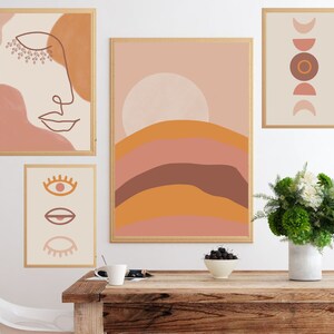 May include: Four framed abstract art prints with a boho aesthetic. The prints feature a line drawing of a face, a sun with a landscape, a series of circles, and a series of eyes. The prints are hung on a white wall above a wooden table with a vase of flowers and a bowl of fruit.