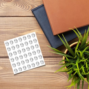 May include: A sheet of 64 black and white alarm clock stickers on a white background. The stickers are arranged in a grid pattern.