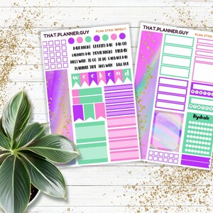 May include: Two planner sticker sheets with a vibrant design. The sheets feature a purple, pink, and teal colour scheme with various shapes and text, including "THAT.PLANNER.GUY" and "weekend". A potted plant is in the lower left corner.