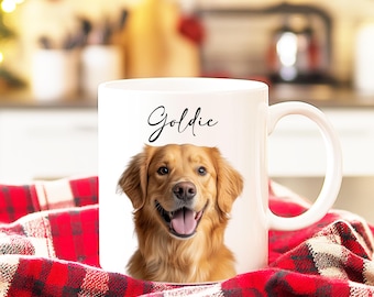 Op de afbeelding: Witte keramische koffiemok met een foto van een golden retriever hond en de naam "Goldie" gedrukt in zwarte cursieve letters.