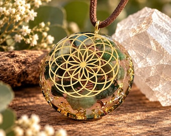 May include: A circular pendant on a brown cord featuring a gold-coloured geometric flower of life pattern embedded in clear resin. The interior contains green stone fragments, copper wire coils, and gold-coloured metallic flakes throughout the resin.