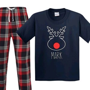 May include: Navy blue pajamas with a red and black plaid pattern. The top features a white reindeer design with a red nose and the name "Mark" written below.