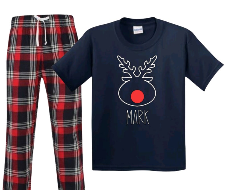 May include: Navy blue pajamas with a red and black plaid pattern. The top features a white reindeer design with a red nose and the name "Mark" written below.