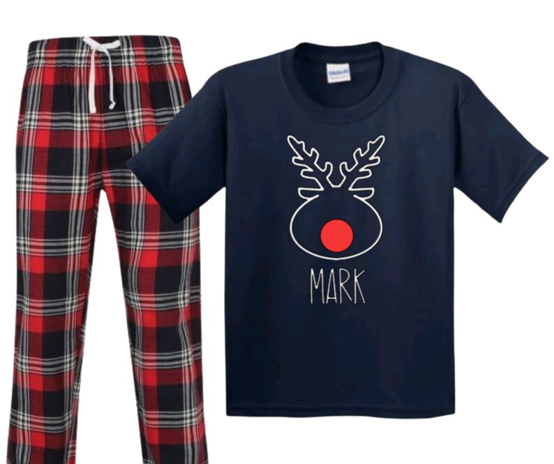 May include: Navy blue pajamas with a red and black plaid pattern. The top features a white reindeer design with a red nose and the name "Mark" written below.
