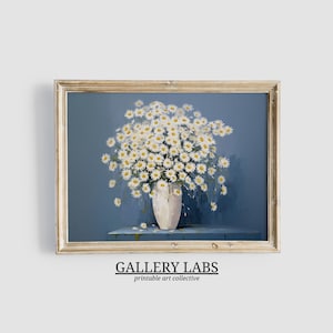 May include: A framed art print featuring a bouquet of white daisies with yellow centers in a light-colored vase, set against a solid blue background. The text GALLERY LABS printable art collective is printed in black below the frame.