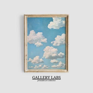 May include: A vertical rectangular framed print featuring a light blue sky filled with fluffy white cumulus clouds. The frame is a weathered, light-toned wood. Below the frame, the text reads GALLERY LABS printable art collective.