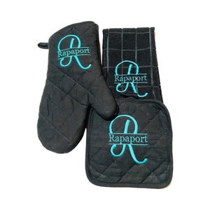 May include: A black quilted oven mitt, pot holder, and tea towel set with the name "Rapaport" embroidered in turquoise on each piece.