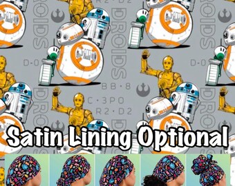 May include: A grey and white patterned fabric featuring Star Wars characters, including R2-D2, C-3PO, and BB-8. The fabric is designed for making surgical caps, with five different styles shown: Euro, Ponytail, Bouffant, Tie Back, and High Bun. The text "Satin Lining Optional" is printed on the fabric.