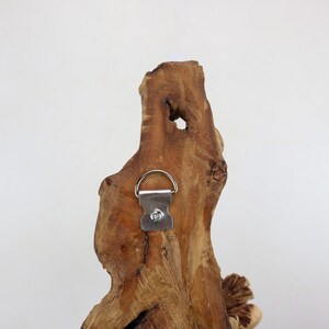 May include: A piece of driftwood with a metal hanging hook attached to the back. The wood is a light brown color and has a natural, rustic look.