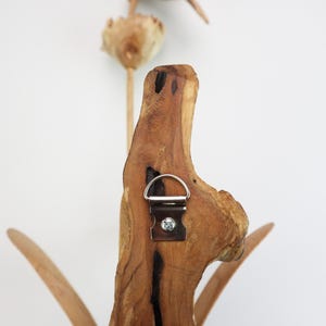 May include: A wooden wall decor featuring a stylized flower design with a metal hanging hook on the back.