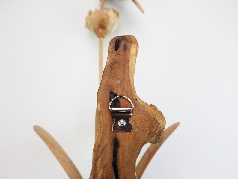 May include: A wooden wall decor featuring a stylized flower design with a metal hanging hook on the back.
