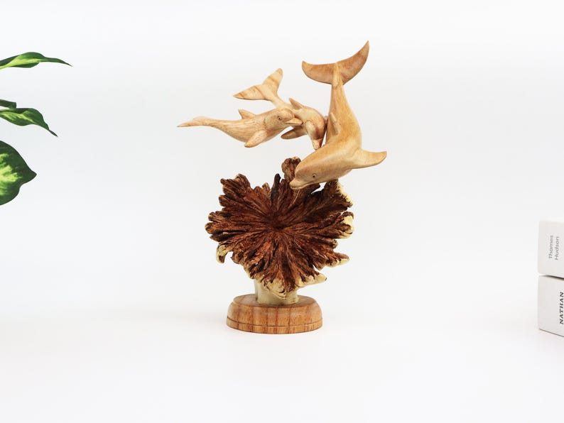 May include: A wooden sculpture of three dolphins leaping out of the water, with a brown wooden base that resembles coral.