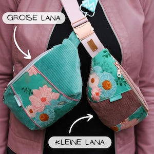 Könnte beinhalten: Zwei Umhängetaschen mit der Aufschrift GROSE LANA und KLEINE LANA. Die größere Tasche ist aus türkisfarbenem Cord mit einer geblümten Tasche. Die kleinere Tasche kombiniert türkisfarbenen Blumenstoff mit malvenfarbenem Cord und Reißverschlüssen.
