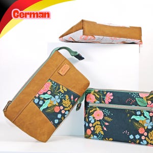 Pode incluir: Três bolsas com fecho de correr que combinam um material liso em tom castanho e um tecido verde-azulado escuro com um padrão floral de flores cor-de-rosa, azuis e amarelas e folhas verdes. Cada bolsa tem um fecho de correr verde-claro.