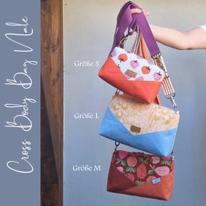 Può includere: Tre borse a tracolla con cinghie regolabili, etichettate come Größe S, L e M. La borsa superiore presenta una stampa di fragole e base arancione, quella centrale un motivo floreale giallo e base blu, quella inferiore una stampa di frutta e base ruggine.