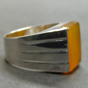 May include: A silver ring with a large, rectangular, orange gemstone.