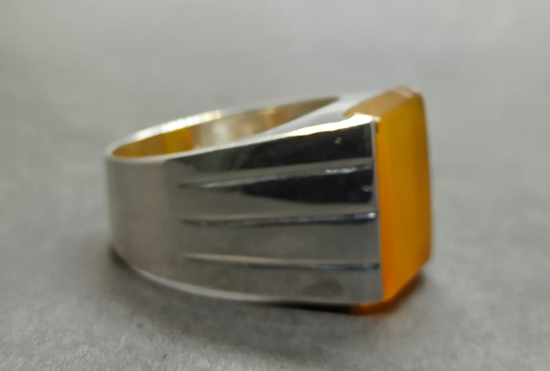 May include: A silver ring with a large, rectangular, orange gemstone.