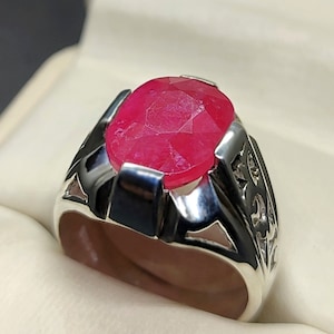 May include: A silver ring featuring a large, oval-shaped, faceted, pink gemstone.
