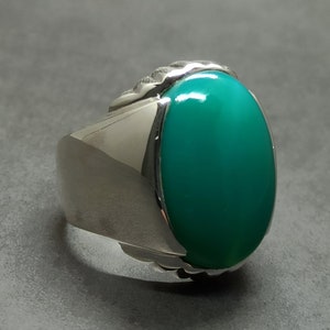 May include: A silver ring with a large oval green gemstone set in a textured silver band.
