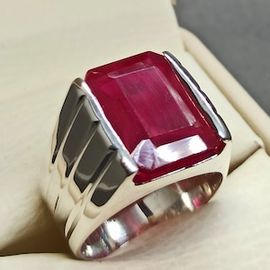 May include: A silver ring featuring a large, rectangular, red gemstone.