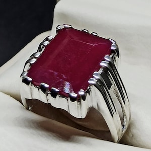 Puede incluir: Un anillo de plata con una gran piedra preciosa roja rectangular.