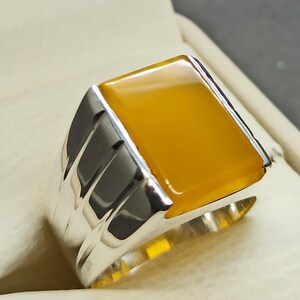 May include: A silver ring with a yellow gemstone. The ring has a textured band.