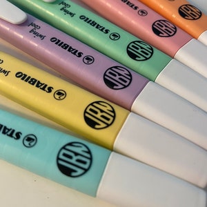 Pu&ograve; includere: Un set di cinque evidenziatori STABILO swing cool in tonalit&agrave; pastello arancione, rosa, verde, giallo e blu. Ogni evidenziatore presenta un cappuccio bianco, una clip da taschino e un logo circolare nero con le lettere JBN sul fusto.