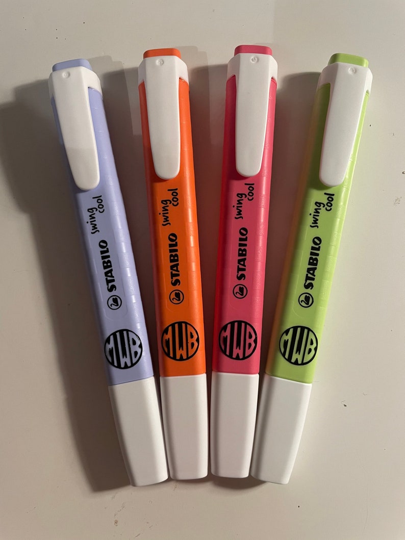Pu&ograve; includere: Quattro evidenziatori Stabilo Swing Cool nei colori viola pastello, arancione, rosa e verde chiaro. Ogni penna presenta un cappuccio bianco con clip, testo nero con scritto STABILO swing cool, un logo a cigno e un monogramma circolare con le lettere MWB.