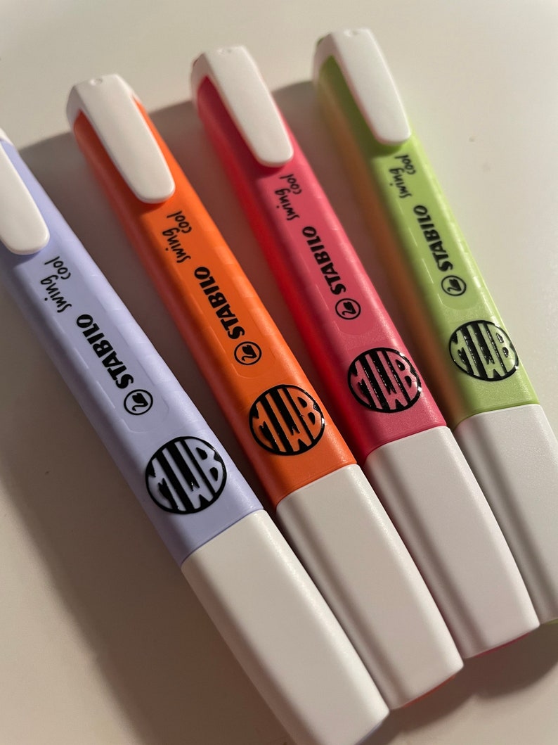 Pu&ograve; includere: Quattro evidenziatori Stabilo Swing Cool nei colori pastello viola, arancione, rosa e verde chiaro. Ogni pennarello presenta un cappuccio bianco, una clip da taschino bianca e un logo circolare nero con le lettere MWB sul corpo colorato.