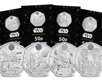 May include: A collection of Star Wars 50p coins featuring iconic characters and scenes. The coins are silver-colored and displayed with their black packaging. The packaging has the Star Wars logo and the words "United Kingdom" and "50p".