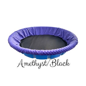 May include: A round, blue, plastic pool with a purple and black padded liner. The liner has a textured, dotted pattern. The text "Amethyst/Black" is written below the pool.