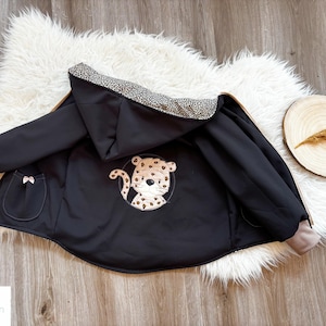 Könnte beinhalten: Schwarze Kapuzenjacke mit Leopardenmuster an der Kapuze und einem niedlichen Leoparden-Applikationen auf der Rückseite. Die Jacke hat einen Reißverschluss und zwei Taschen.