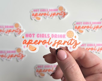 Może przedstawiać: Wiele naklejek z tekstem "HOT GIRLS DRINK aperol spritz" w różowych i pomarańczowych literach z małym graficznym obrazkiem plasterka pomarańczy.
