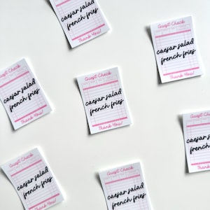 Pu&ograve; includere: Sei scontrini bianchi per ospiti con linee rosa e testo nero. Ogni scontrino dice "Guest Check" in alto e "Caesar salad french fries" in corsivo. In fondo a ogni scontrino c'&egrave; scritto "Thank You!"