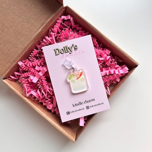 May include: A clear acrylic cocktail charm with lime and chilli pepper details, suspended from a silver-coloured chain. The charm is attached to a pink card with the text "Dolly's doodles" and "kindle charm". Presented in a brown box with pink shredded paper.